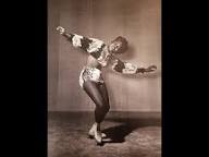 Mabel Fairbanks in a light-colored show costume with arms outstretched on the ice during an ice revue performance